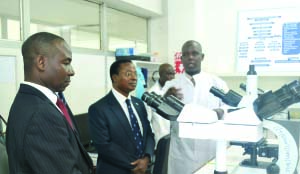 • TROPICAL Diseases Research Centre (TDRC) Chief Technologist Daniel Mutale (in a white coat) showing Health Permanent Secretary David Misheck Chikamata (center) and TDRC director Modest Mulenga the Ticking Microscope in the Parasitology laboratory during his tour of the facility in Ndola on Thursday this week. Picture By CHATULA KAMPO.