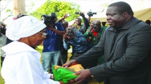 • SPORTS Minister, Chishimba Kambwili hands over a Zambian flag which was draped over late veteran football commentator and journalist, Dennis Liwewe’s casket to widow, Sylvia during the burial in Lusaka yesterday. Picture by JEAN MANDELA