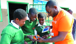•A member of staff at SunnyMoney explains to Mulalika Basic School pupils in Chongwe how the Solar Sunking Mobile charger works.