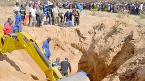 •SCORES of on-lookers watch as fire brigade officers and police attempt to dig up the body of a woman buried alive in Kitwe yesterday. Picture by MOFFAT CHAZINGWA