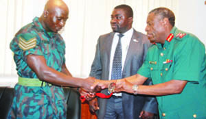 • JUDOKA Boas Munyonga (left) presents the bronze medal he won at the 2014 Commonwealth Games in Scotland to Zambia National Service (ZNS) commandant, Nathan Mulenga in Lusaka yesterday as Zambia Judo Association president Alfred Foloko looks on. Picture courtesy of ZNS
