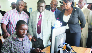 •A BLIND teacher at the Lions School for the Visually Impaired testing a computer before Copperbelt Minister Mwenya Musenge (left), Minister of Transport, Works, Supply and Communications Yamfwa Mukanga and ZICTA director-general Margaret Chalwe-Mudenda (right).