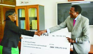 • Secretary to the Treasury, Fredson Yamba (right) receives a dummy cheque from Zambia Sugar managing director Rebecca Katowa at the Ministry of Finance in Lusaka yesterday. Picture by STEPHEN KAPAMBWE