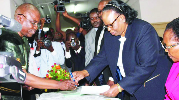 • GREEN Party leader Peter Sinkamba (left) filing in his presidential nomination papers before acting Chief Justice Lombe Chibesakunda (right) in Lusaka yesterday.