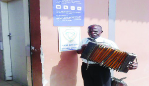 • EVANGELIST Joseph Chisenga playing his accordion at the entrance to Pick n’ Pay in Chingola. Picture by RACKSON SHAMUTUKU