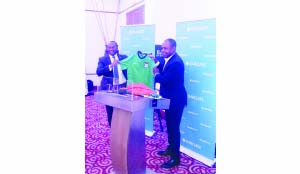 •FOOTBALL Association of Zambia president Kalusha Bwalya (right) presents Chipolopolo replica jerseys to Barclays Bank managing director, Saviour Chibiya during the 2015 Barclays Cup draw at Taj-Pamodzi Hotel in Lusaka yesterday. (Inset) Barclays Cup trophy on display. Pictures by SHAMAOMA MUSONDA