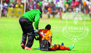 •ZESCO United midfielder, Mwape Mwelwa (seated) receives medical attention from team physiotherapist, Chuma Mwinga after being hit by an object at Shinde Stadium in Mufulira during an abortive MTN-FAZ Super League Week 19 match against Mufulira Wanderers. Picture by ZESCO UNITED FC