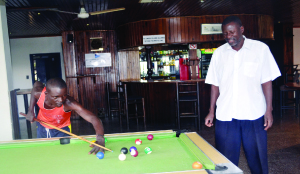 •KAFUBU Dam where the Ndola boating club is situated. (Inset) Boating club senior man, Milner Simukonda (standing)  and a patron Mwewa Chanda playing pool in the club lounge. Pictures by YVONNE CHATE.