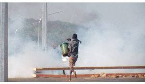 •A BOY is captured running with a bucket during riots in Chipata yesterday. Tenants ran amok on the Great East Road, protesting evictions from houses owned by Contract Haulage. Pictures by VINCENT SOKO