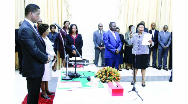 • PRESIDENT Lungu (left) listens as Lady Justice Winnie Mwenda (right) takes the oath of office during a swearing-in ceremony at State House in Lusaka yesterday. Picture by SALIM HENRY/STATE HOUSE